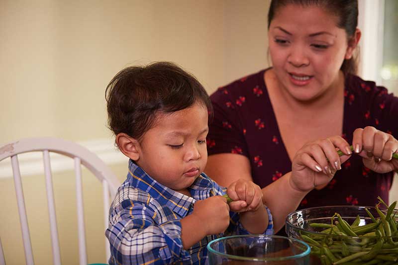toddler snapping green beans in grocery store